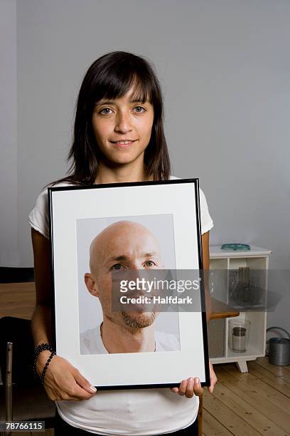 a woman holding a framed photograph - long hair photos stock-fotos und bilder