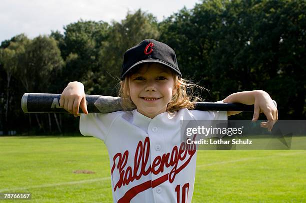 a young girl holding a baseball bat on her shoulders - divisa da baseball foto e immagini stock