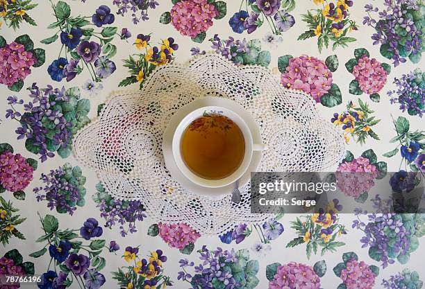 a cup of tea on a floral tablecloth - table cloth stockfoto's en -beelden
