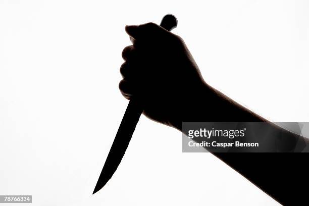 a silhouette of a hand holding a knife - threats bildbanksfoton och bilder