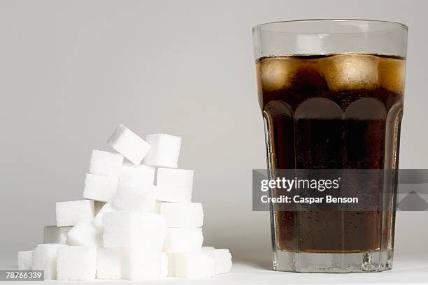 a glass of coke and a heap of sugar cubes - sugar in glass stock pictures, royalty-free photos & images