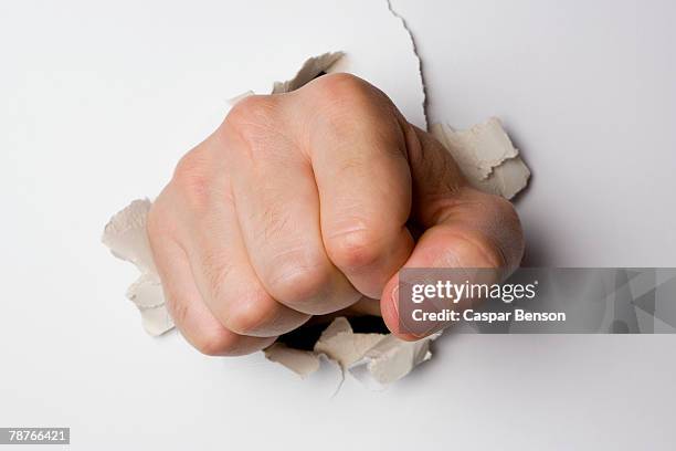 a fist breaking through a wall - breaking through wall stockfoto's en -beelden
