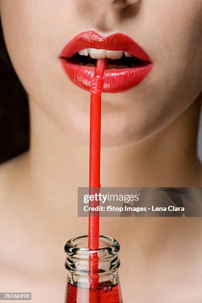 a woman wearing red lipstick drinking from a red straw - straw lips stock pictures, royalty-free photos & images