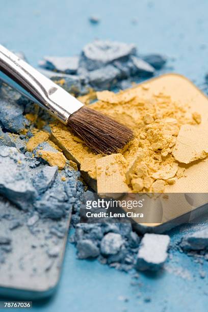 a make-up brush with blue and yellow eyeshadow - makeup pile stock pictures, royalty-free photos & images