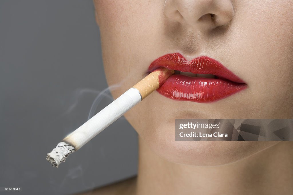 A woman wearing red lipstick and smoking a cigarette