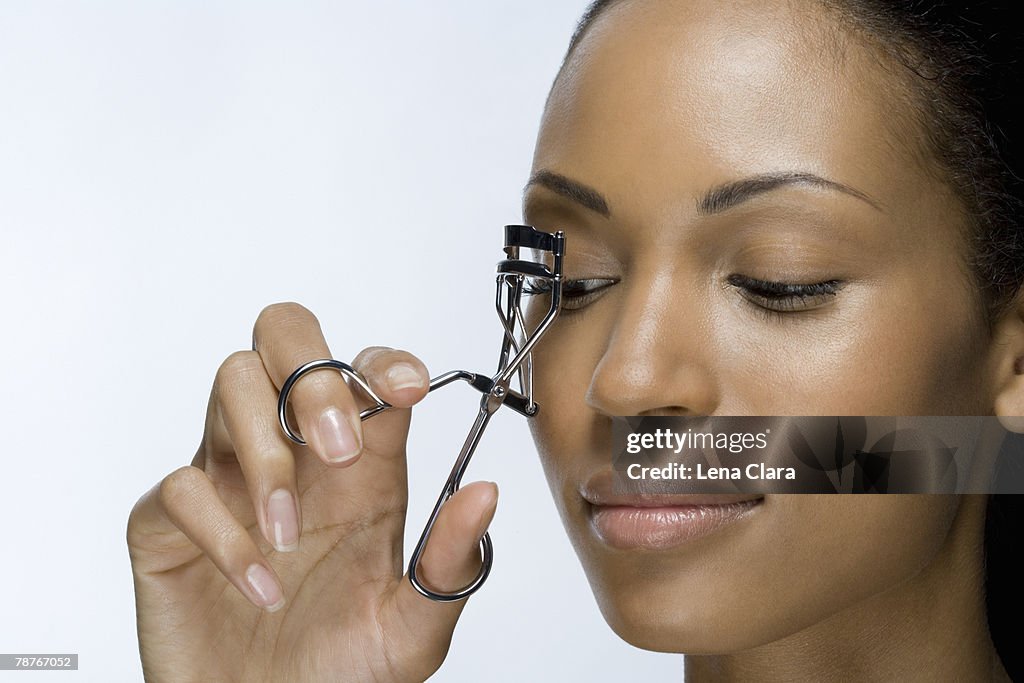 A woman using eyelash curlers