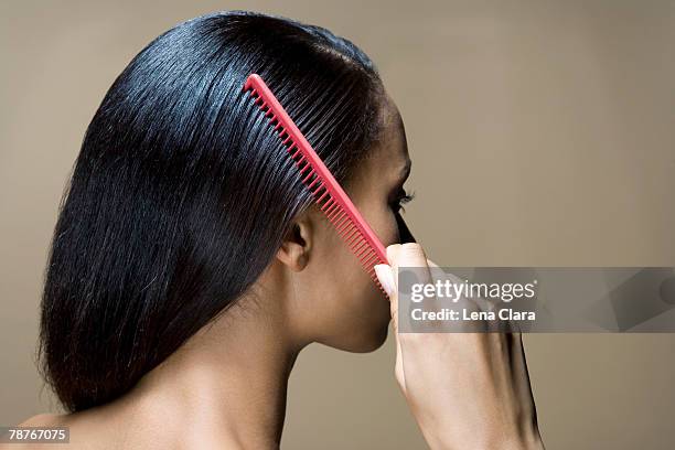 a woman combing her hair - black woman hair back stock pictures, royalty-free photos & images