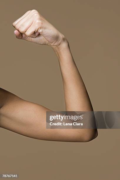 a woman flexing her bicep - flexionar los músculos fotografías e imágenes de stock