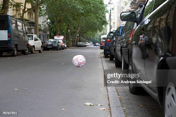 a football bouncing across the street - street football stock pictures, royalty-free photos & images