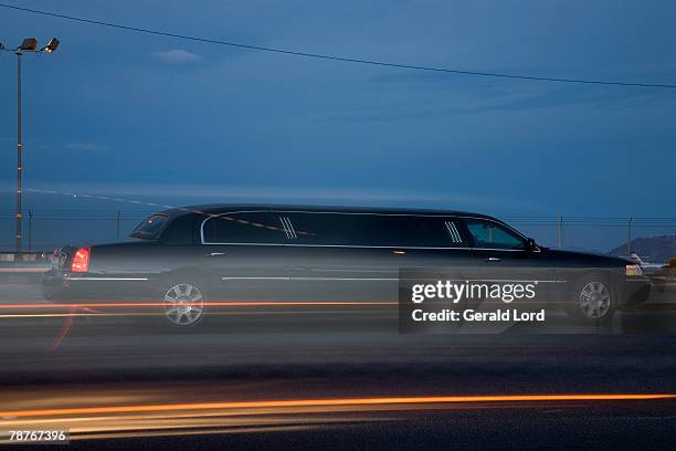 a limousine driving along the road - limousine fotografías e imágenes de stock