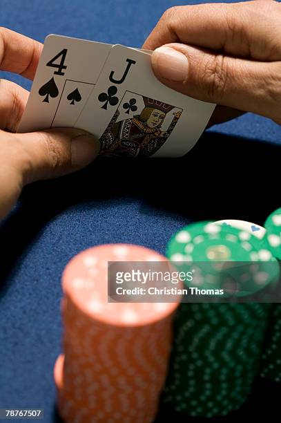 hands holding playing cards in front of stacks of gambling chips - クラブのジャック ストックフォトと画像