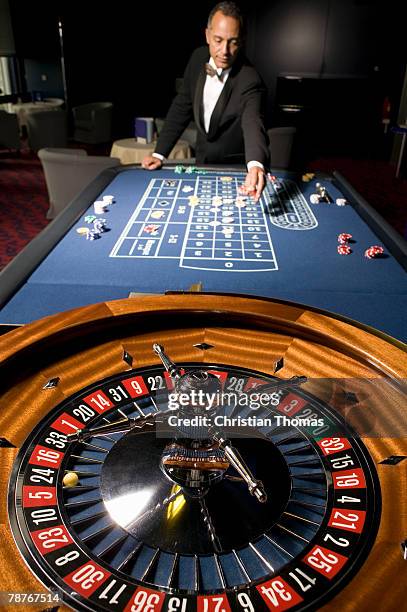 man placing a bet at the roulette table - gambling table stock pictures, royalty-free photos & images