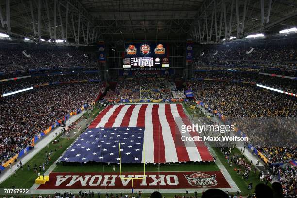 An American flag is spread across the field during the national anthem before the game between the Oklahoma Sooners and the West Virginia...