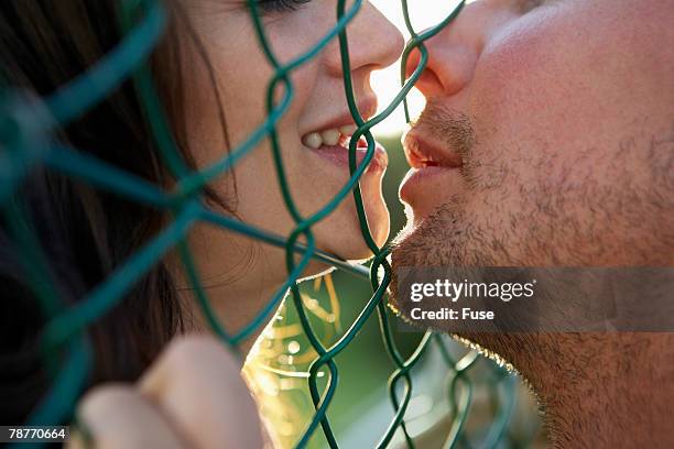 affectionate couple with fence between them - extreme close up kiss stock pictures, royalty-free photos & images
