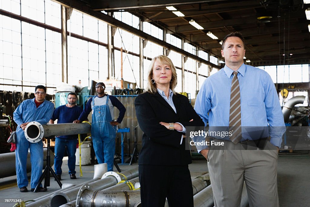 Businesspeople and Workers in a Factory