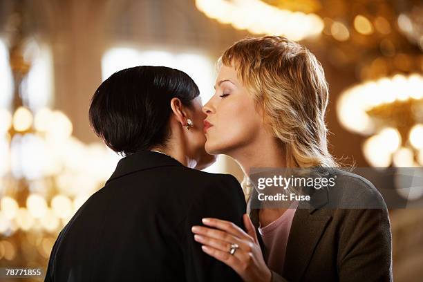 woman kissing one another on the cheek - cheek kiss stock pictures, royalty-free photos & images