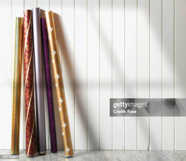 rolls of holiday wrapping paper against wall - roll up stockfoto's en -beelden