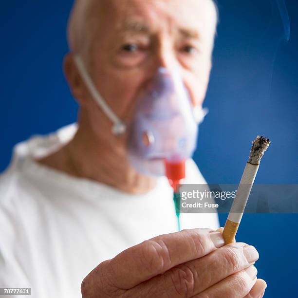 elderly patient wearing oxygen mask and smoking cigarette - équipement d'assistance respiratoire photos et images de collection