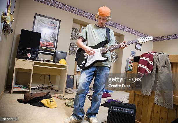 teenage boy playing guitar - messy bedroom stockfoto's en -beelden