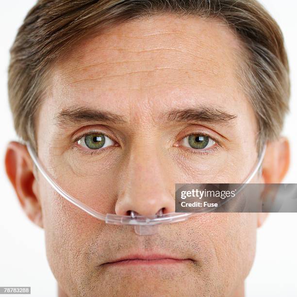 man wearing nasal cannula for supplemental oxygen - tubo de oxígeno fotografías e imágenes de stock
