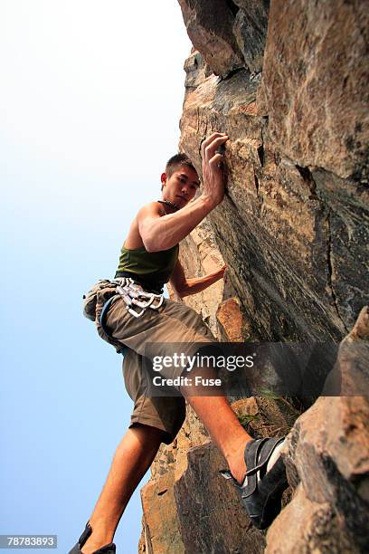 young man rock climbing - physical geography ストックフォトと画像