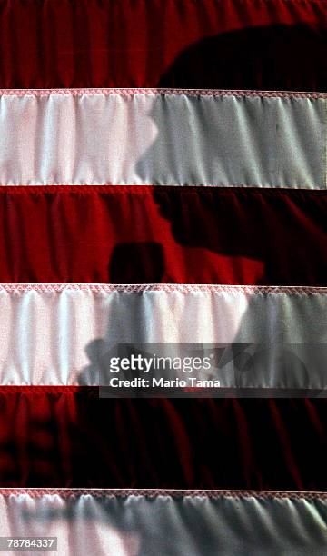 Republican presidential contender U.S. Sen. John McCain's shadow is seen on a flag as he speaks to supporters during a campaign stop at VFW Post...