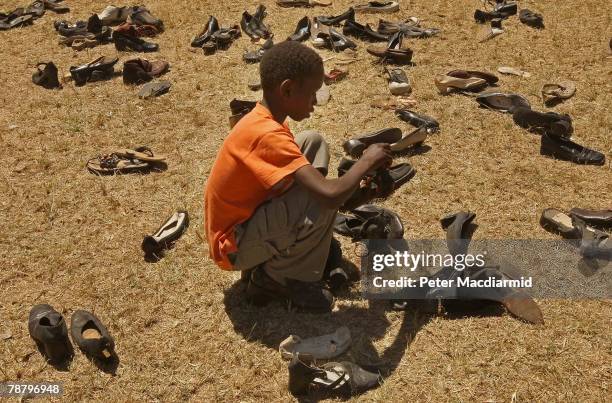 Kikuyu boy looks for shoes donated by local people at the Nakuru show ground on January 7, 2008 in Nakuru, Kenya. Local volunteers and charities are...