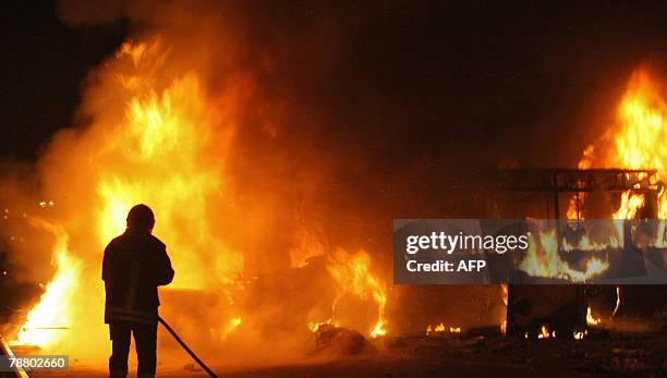 An Italian firefigther tries to extinguish an autobus in fire which was lite up by demonstrators against the Pianura rubbish dump, 07 January 2008 in...