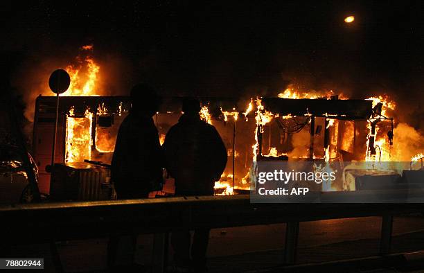 Two people look at a bus which was litten up by demonstrators against the Pianura rubbish dump, 07 January 2008 in Naples. Police in Naples clashed...