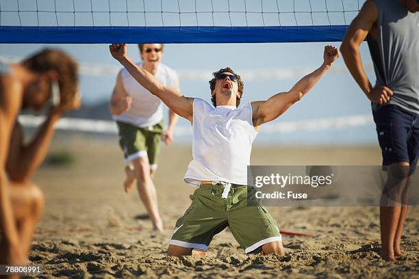 man celebrating during beach volleyball game - beach volleyball stock pictures, royalty-free photos & images