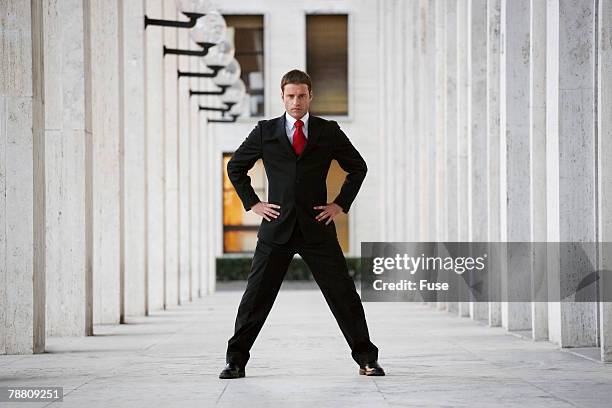 businessman standing in arcade - breitbeinig stehen stock-fotos und bilder