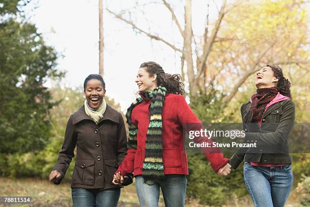 three women walking holding hands - steve prezant stock pictures, royalty-free photos & images