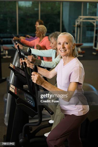 women exercising on an elliptical trainer - happy caucasian woman on elliptical trainer at gym stock pictures, royalty-free photos & images