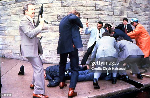 View of armed Secret Service agents around the bodies of policeman Thomas K Delahanty and White House Press Secretary James Brady while the shooting...