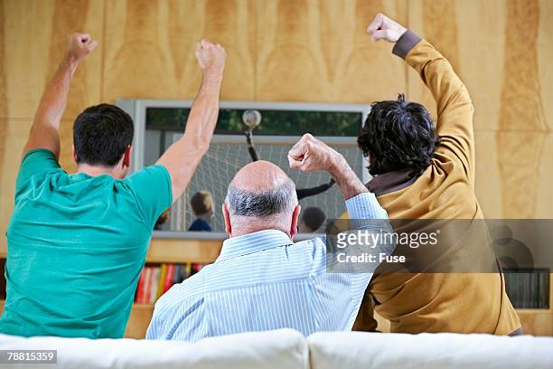 men cheering and watching soccer game on tv - concurso tv fotografías e imágenes de stock