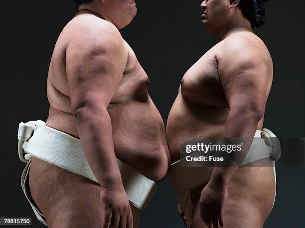 sumo wrestlers standing belly to belly - sumo stock pictures, royalty-free photos & images