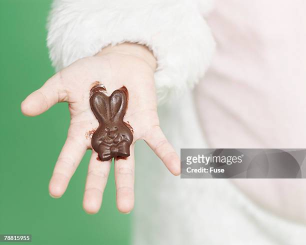 melting chocolate bunny in hand - osterhase schokolade stock-fotos und bilder