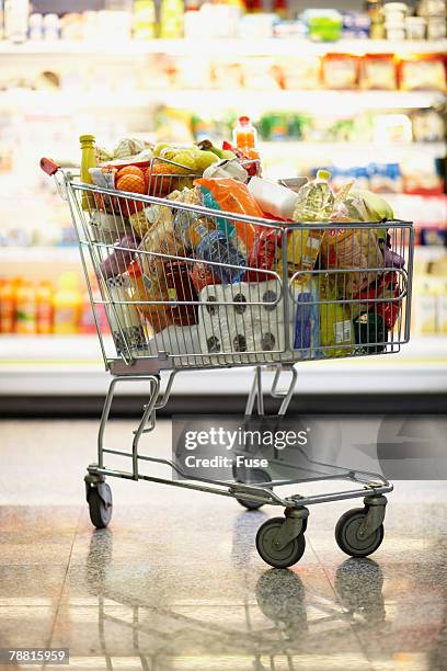 full shopping cart in grocery store - wagon foto e immagini stock