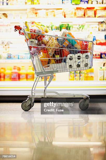 full shopping cart in grocery store - einkaufswagen voll stock-fotos und bilder