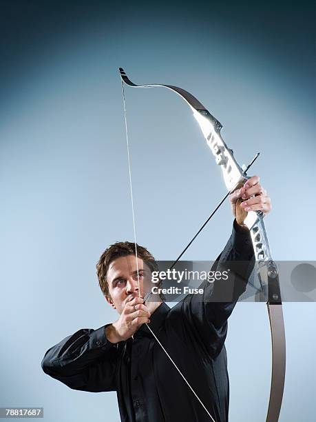 businessman aiming a bow - pfeil und bogen stock-fotos und bilder