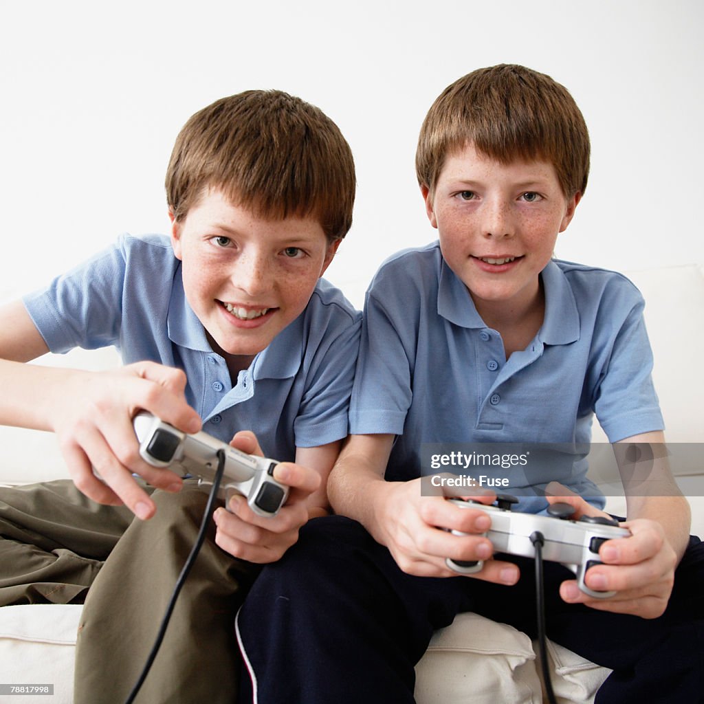 Identical Twin Pre-teen Boys on Sofa Playing Video Game