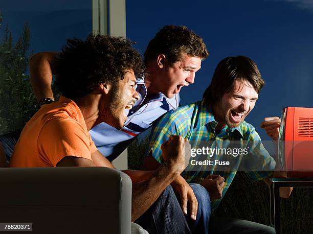 three excited sports fans watching television - tragbarer fernseher stock-fotos und bilder