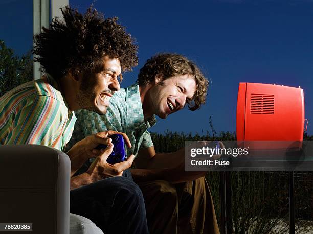 two excited men playing console game - tragbarer fernseher stock-fotos und bilder