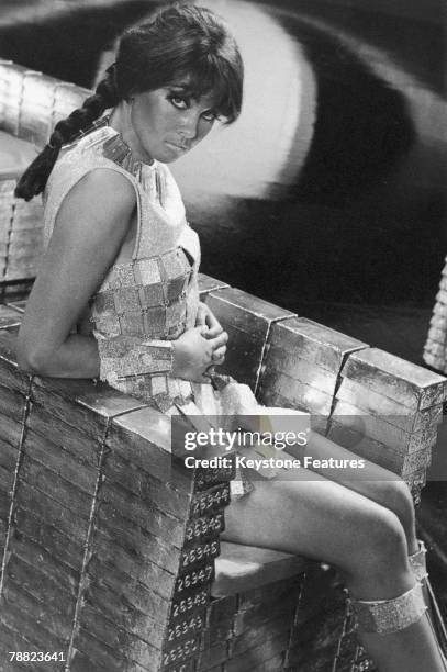 English actress Caroline Munro sitting on a throne of fake gold ingots in a promotional still for 'Casino Royale', directed by Val Guest et al,...