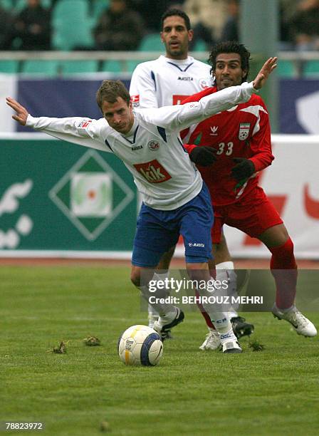 Iran's Milad Meidavoudi vies for the ball with German Bundesliga's Hansa Rostock player Marcel Schied during a friendly match at Tehran's Azadi...