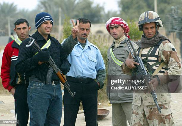 An Iraqi policeman flashes a V-sign as he poses for a picture with members of Al-Sahwa, the so-called Iraqi Awakening Council, and an Iraqi soldier...
