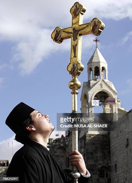 Greek Orthodox clergyman holds a cross during the Orthodox Christmas Eve celebrations outside the Church of the Nativity, believed to be the...