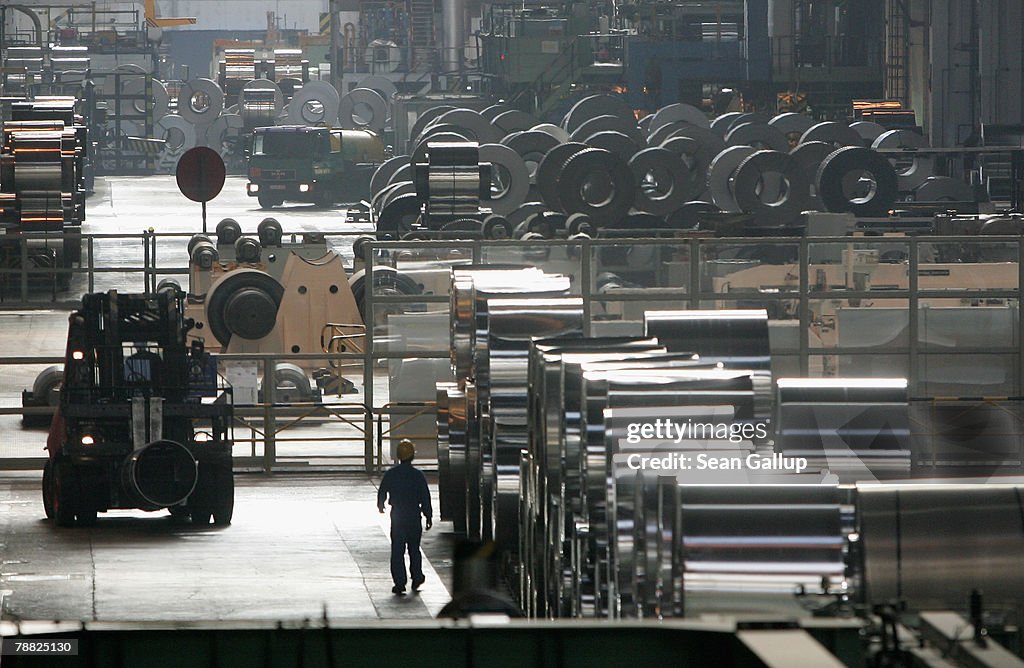 A worker walks among rolls of semi-finished aluminum at the Alcoa ...