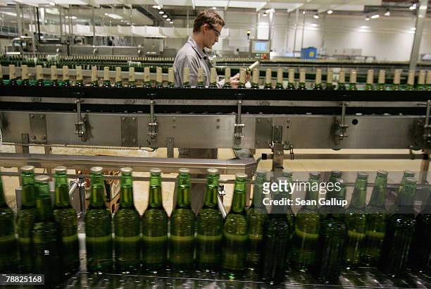 Technician checks a bottle as other bottles of freshly-brewed Pilsner-Urquell lager beer run through the newly-built, ultra-modern bottling plant at...