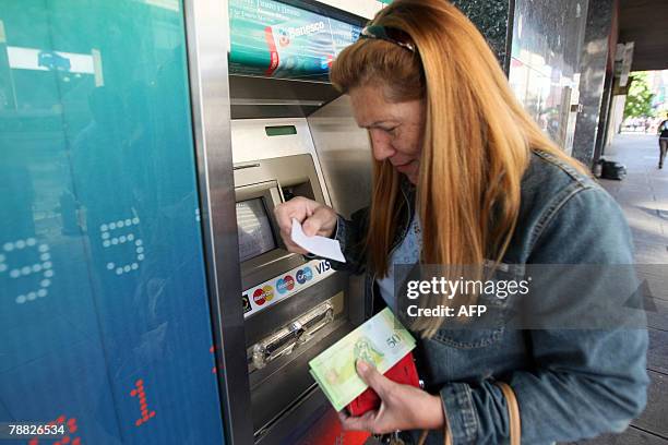 Woman withdraws money from a cash dispenser in Caracas, on January 2nd a day after Venezuela's new currency, the bolivar fuerte , went into...